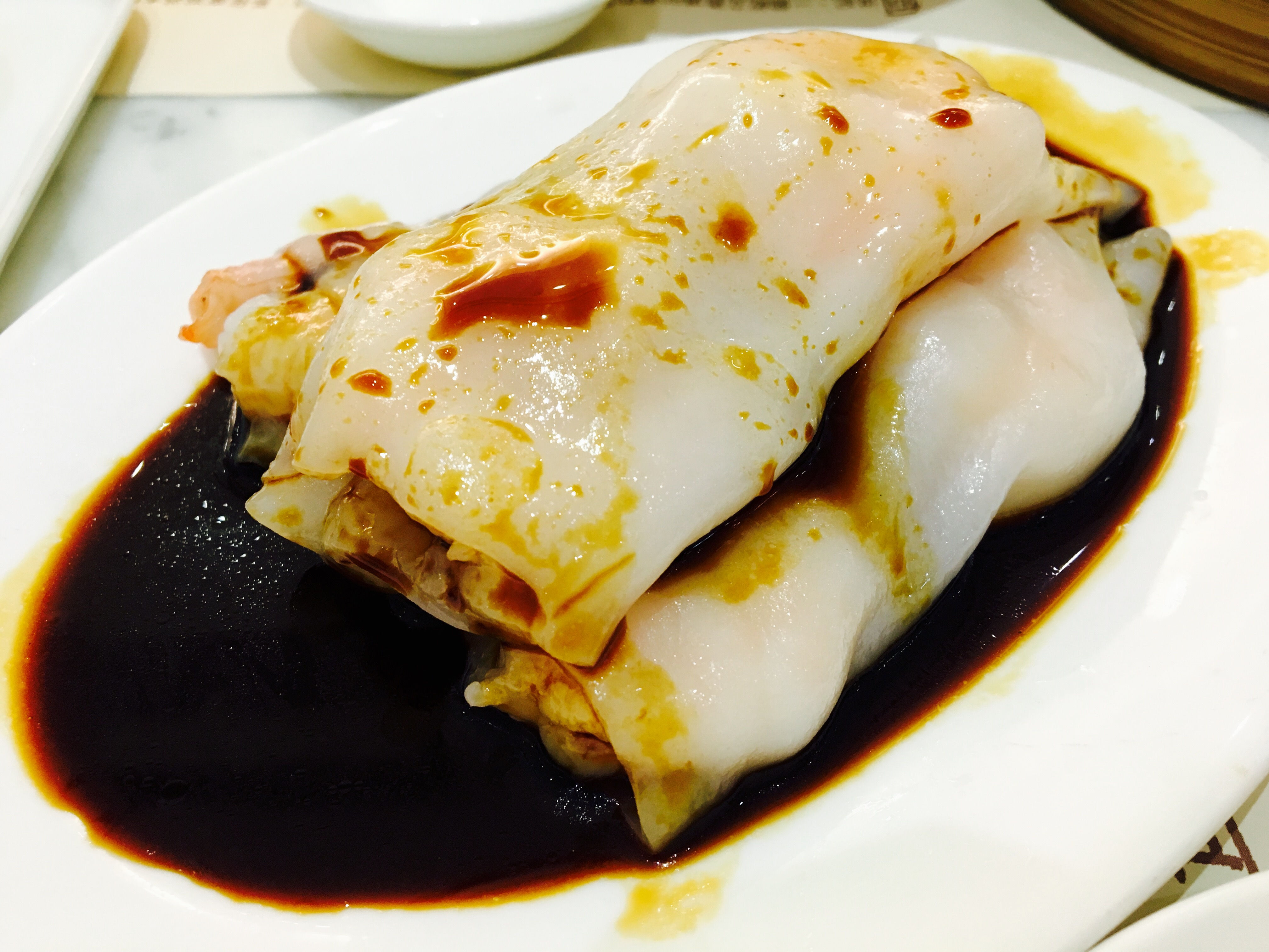 Plate of cheung fun rice noodle rolls with sauce