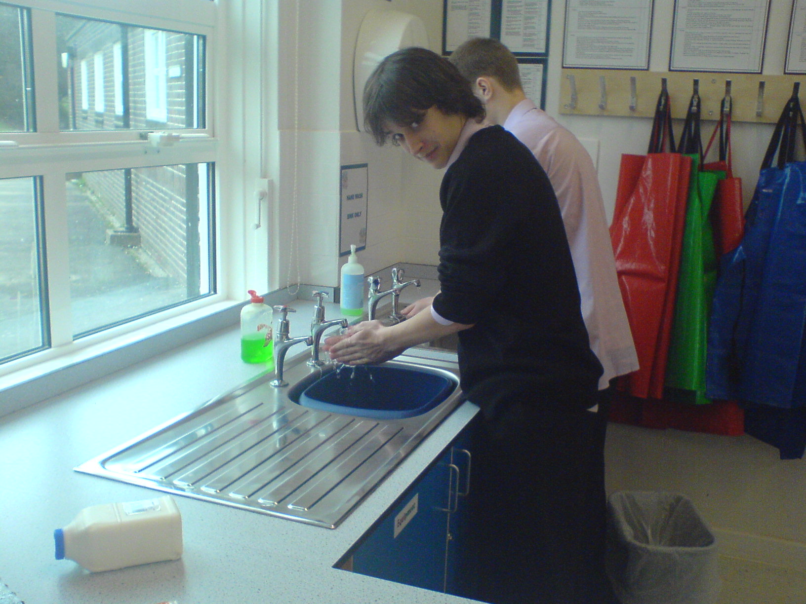 A person washing hands at a kitchen sink before preparing food.